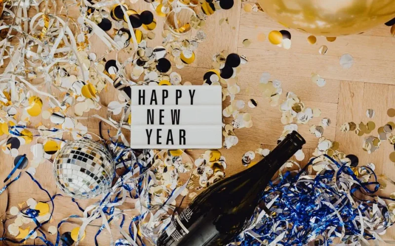 Top view of New Year celebration with champagne, confetti, and lightbox message.