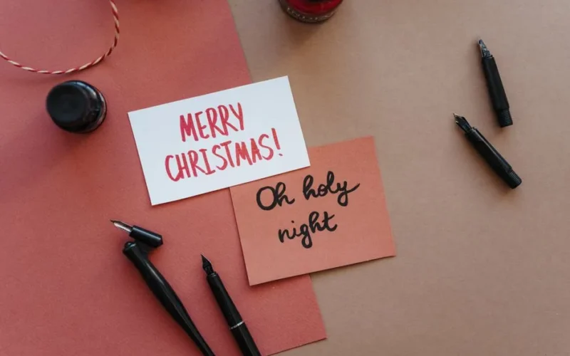 Elegant flat lay of handwritten Christmas cards with fountain pens and ink.