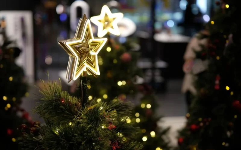 Glowing Christmas tree star topper with festive decorations indoors.