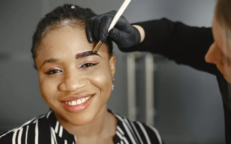 A woman enjoys her eyebrow treatment with a smile, showcasing beauty and self-care.