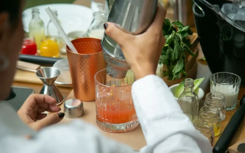 Close-up of hands mixing a cocktail with fresh ingredients at a bar in CDMX.