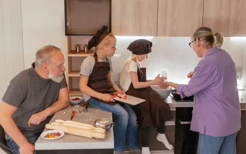 Grandparents cooking with grandchildren in a warm family setting.