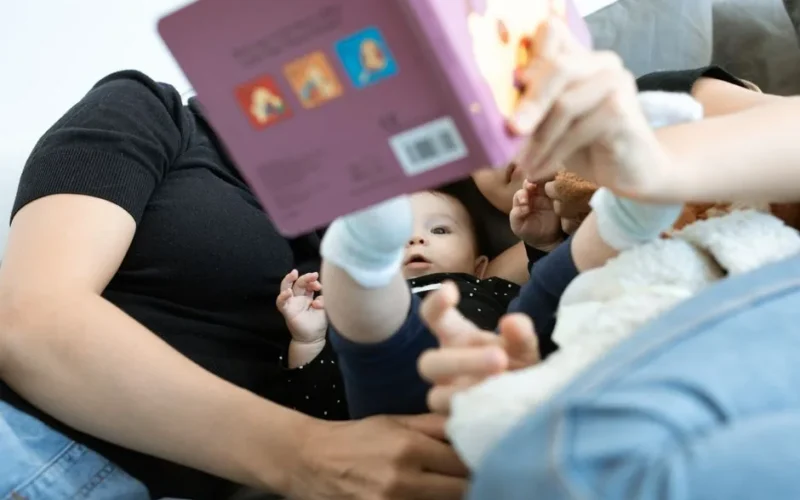 A baby and family reading together, promoting love and education. Cozy indoors setting.