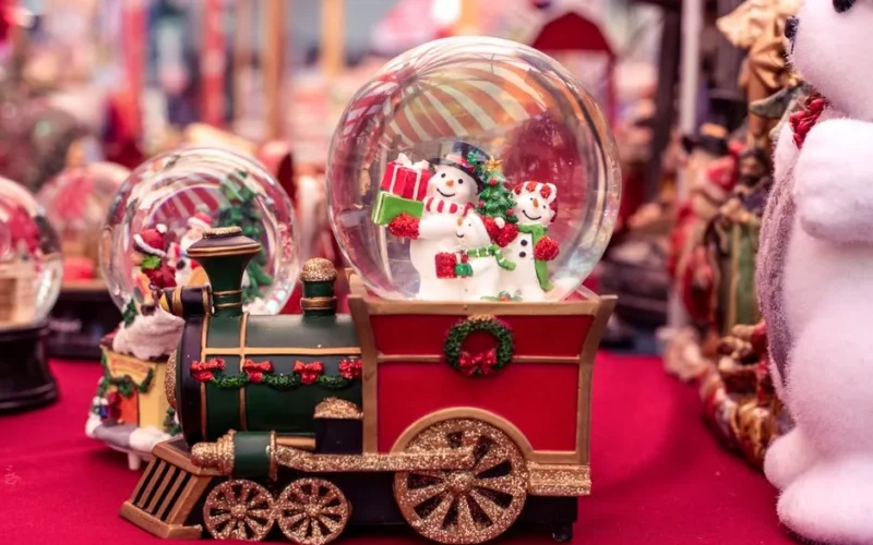 Charming snow globe with snowman on a festive toy train, perfect for Christmas decor.