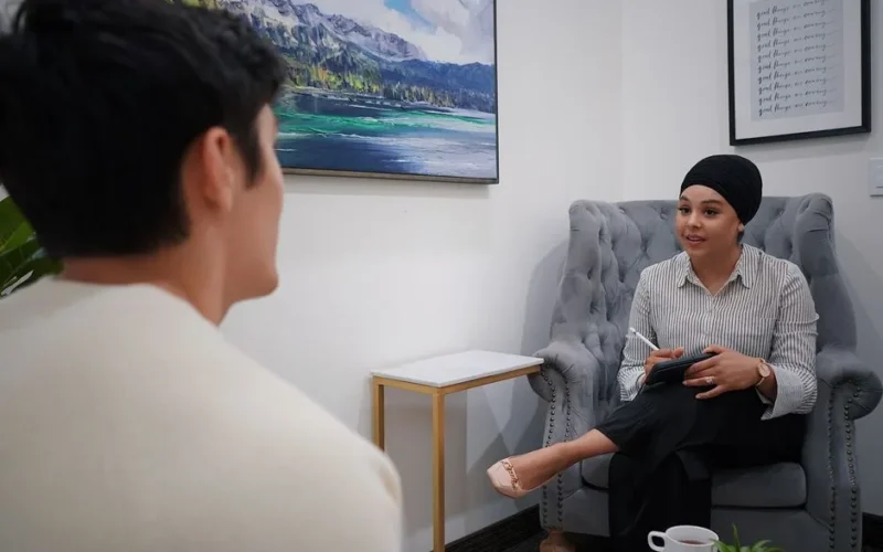 A therapist conducts a one-on-one session with a client in a comfortable office environment.