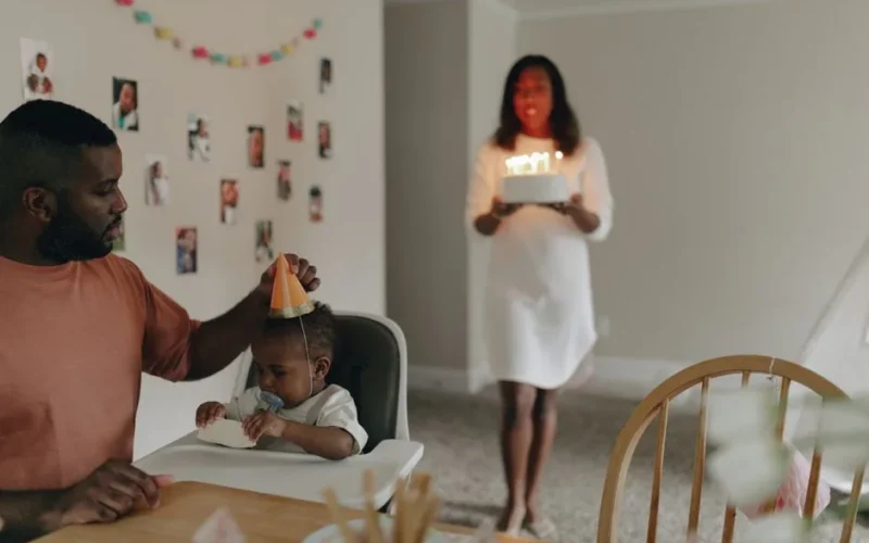 A joyful family celebrating a baby's first birthday with cake and decorations.