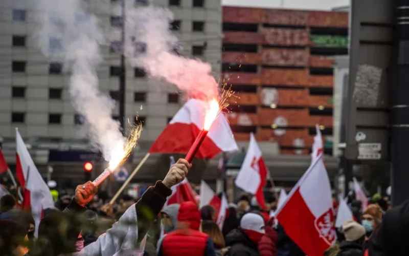 Crowd in Warsaw waving flags and flares during a patriotic demonstration.