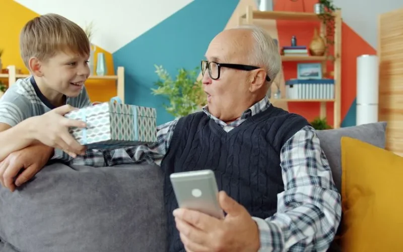 Senior man and boy enjoying a heartwarming gift exchange indoors.