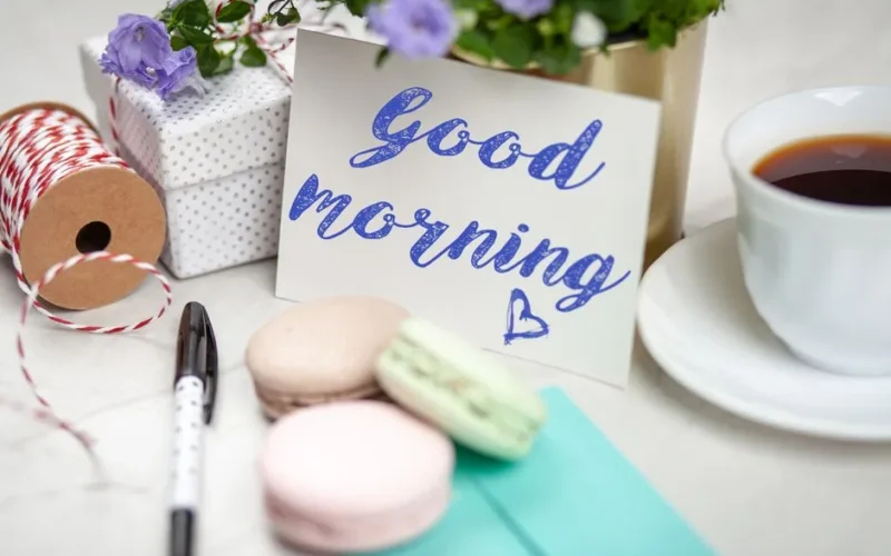 Good morning card with coffee, macarons, and gifts creating a cozy scene.