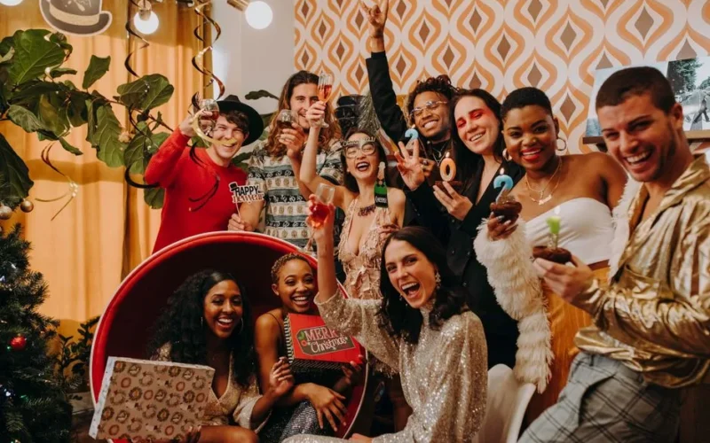 A lively party scene with a diverse group celebrating New Year's Eve indoors with drinks and decorations.