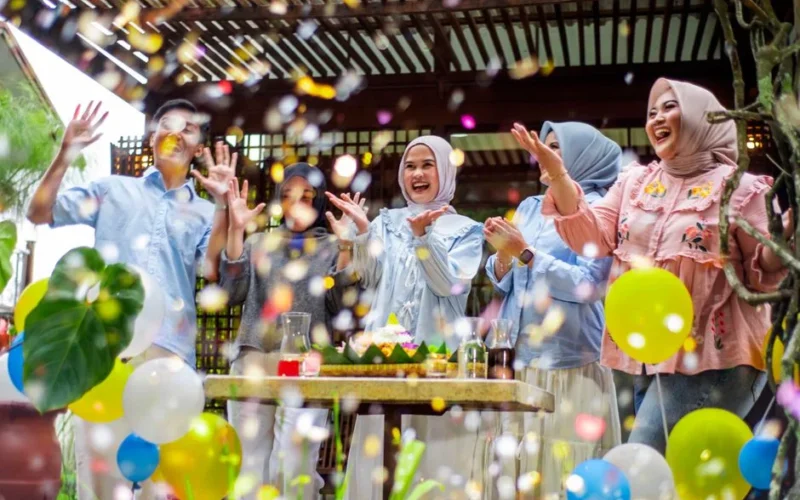 A lively group of friends celebrating outdoors with balloons and confetti, symbolizing joy and togetherness.