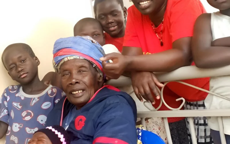 A family portrait in Uganda featuring grandmother, mother, and children. The image illustrates traditional family structures where multiple generations live together, reflecting cultural values of extended family bonds and elder respect