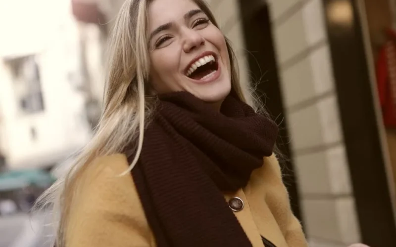 Vibrant portrait of a joyful woman laughing outdoors in winter clothing. Radiates happiness.