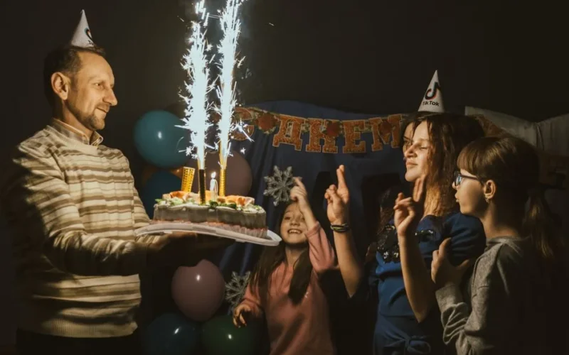 A family celebrating a birthday with a sparkling cake and joyful moments indoors.