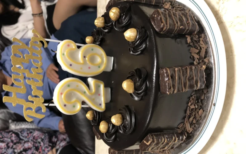 Tim Tams filled on the Side and Nuts filled on top of a Birthday Cake With 2 and 6 Shaped Candles During her Anniversary