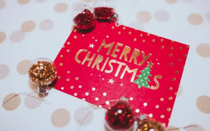 A vibrant red Merry Christmas card surrounded by festive glitter ornaments, perfect for holiday celebrations.