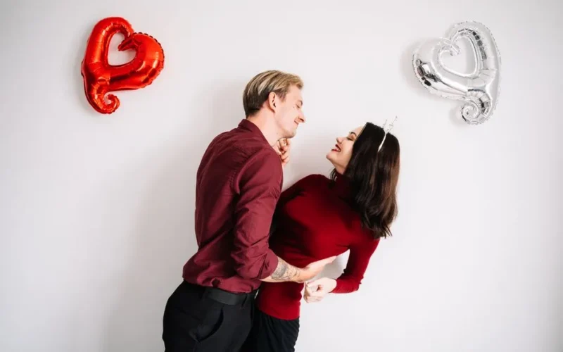 A couple joyfully embracing with heart-shaped balloons, symbolizing romance and love.