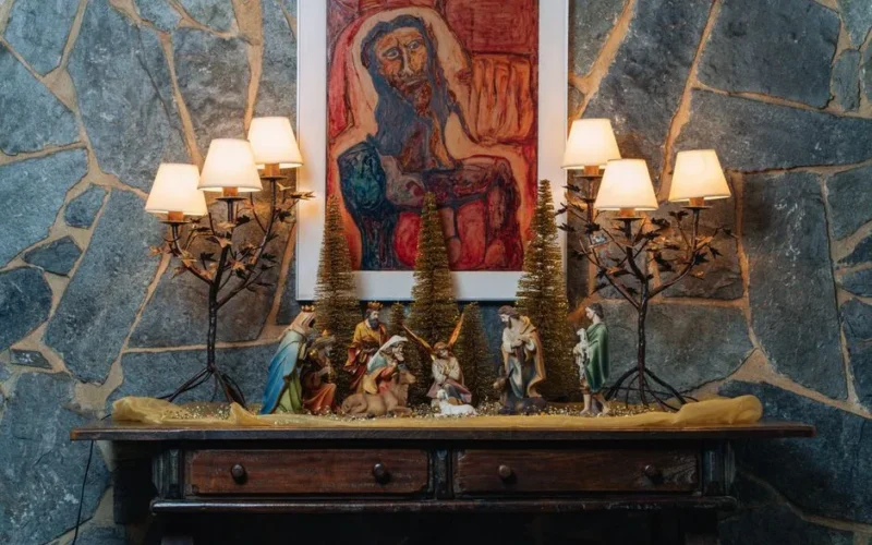 A cozy indoor display featuring a nativity scene, festive lamps, and artful decor.
