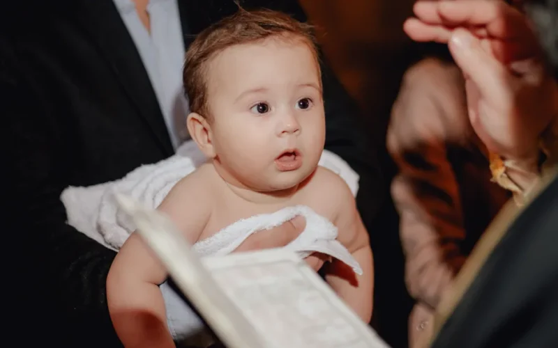 A serene moment during a baby's baptism ceremony, capturing innocence and religious tradition.