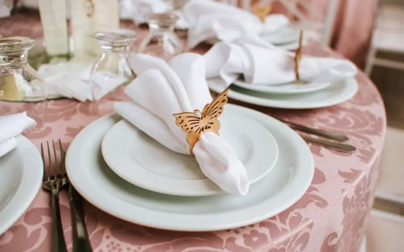 Sophisticated wedding table setting featuring butterfly napkin rings, fine china, and elegant tableware.