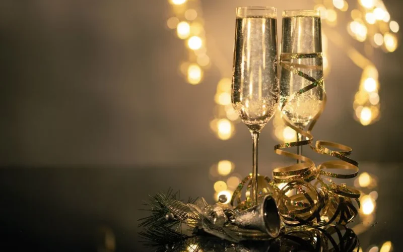 Champagne glasses with ribbons against festive bokeh lights.