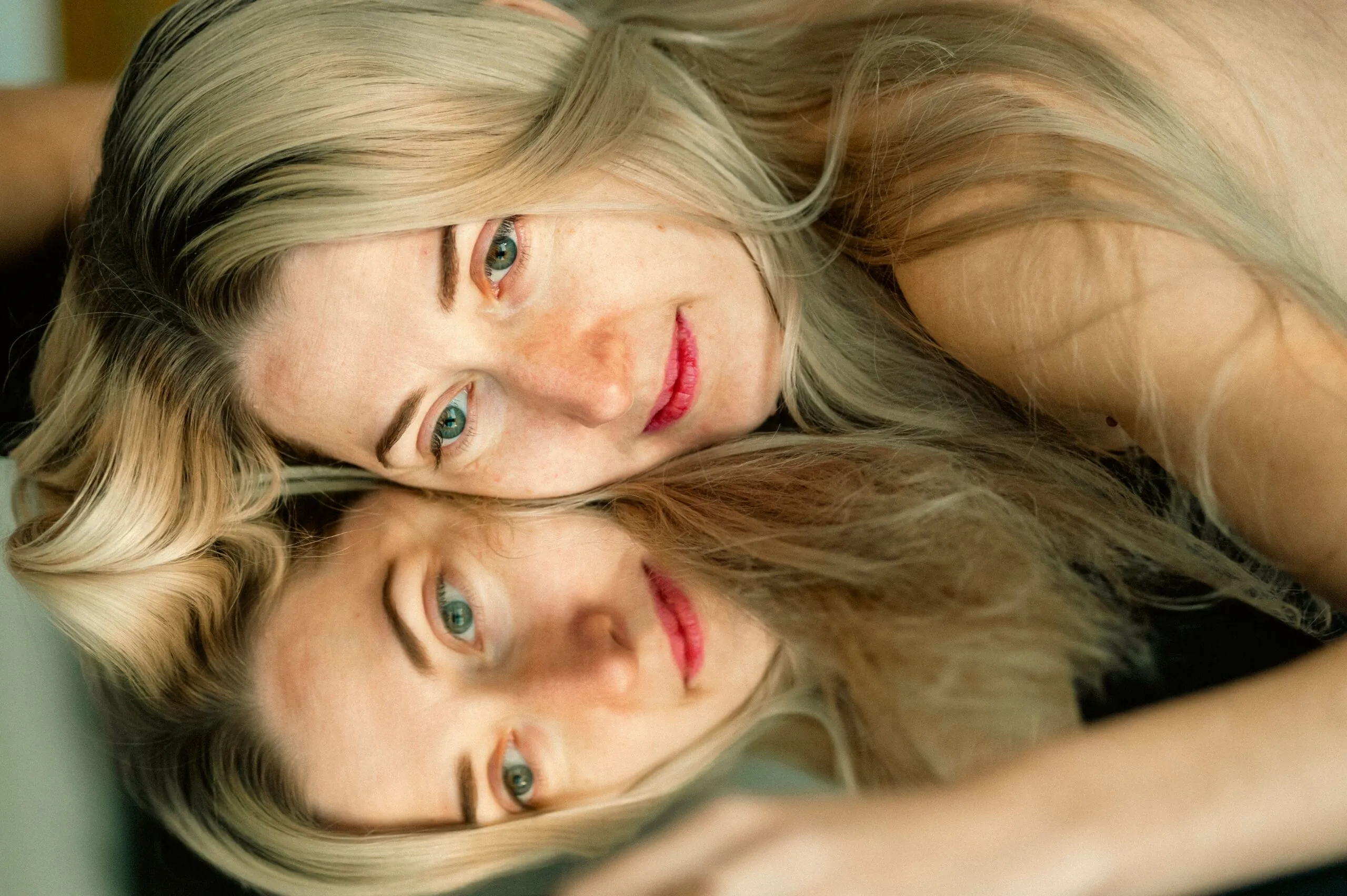 Close-up portrait of a woman with mirror reflection, creating a serene and contemplative mood.