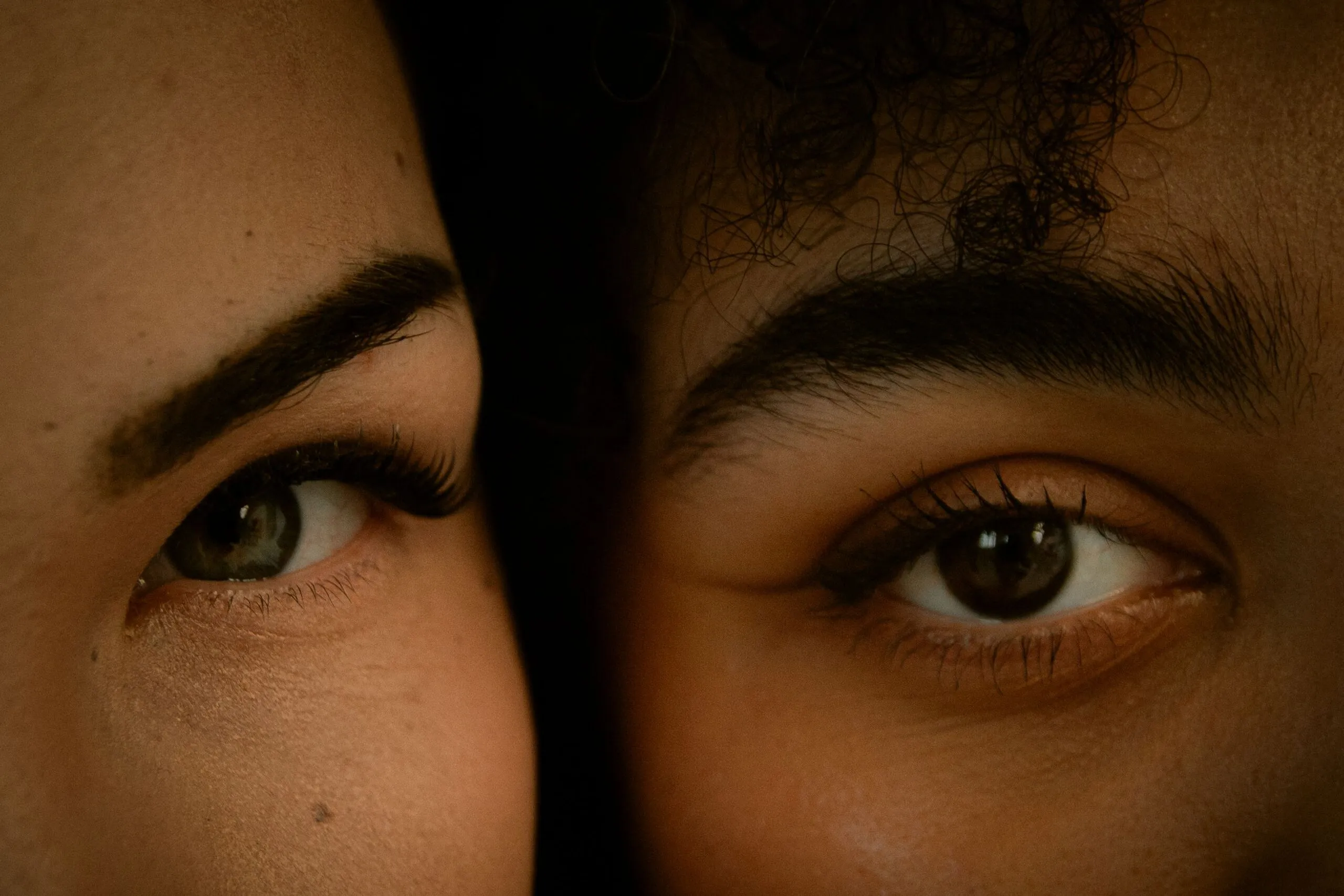 A detailed close-up showing the expressive eyes of two diverse women in natural light.