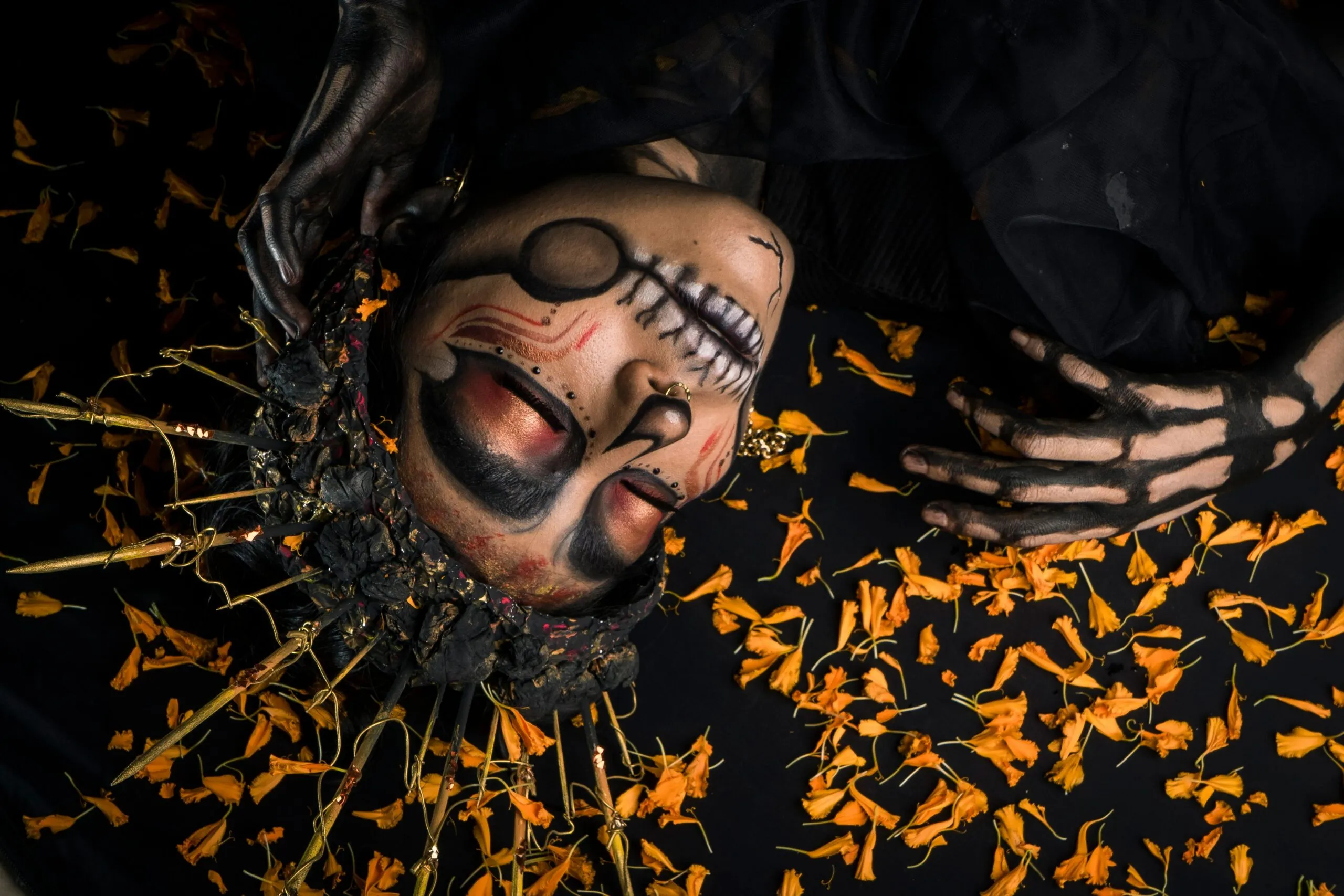 Artistic Day of the Dead makeup surrounded by marigold petals, capturing cultural essence.
