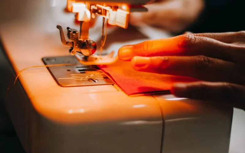 A focused shot of a sewing machine operating with fabric and hand interaction.