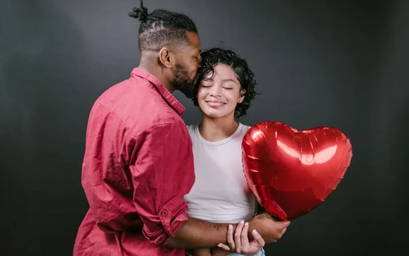 A loving couple embraces while holding a heart-shaped balloon, celebrating romance.