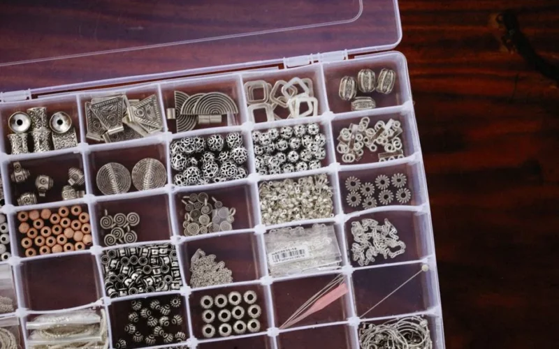 A close-up view of a neatly organized box filled with diverse crafting beads in compartments.