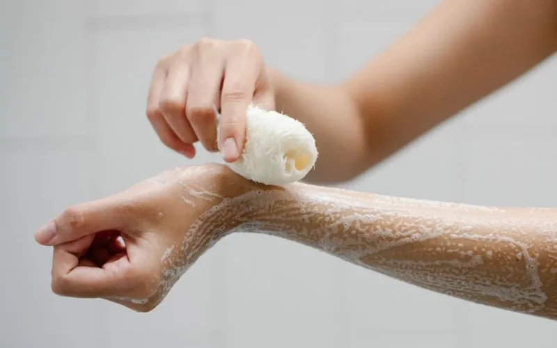 Crop anonymous person using wisp washing arms with soap foam during hygienic procedure