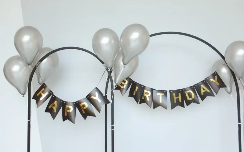 Stylish birthday party decor with silver balloons and black-gold banner.