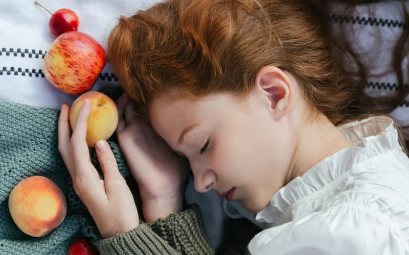 Serene image of a woman with closed eyes holding fruit. Captures tranquility and nature.
