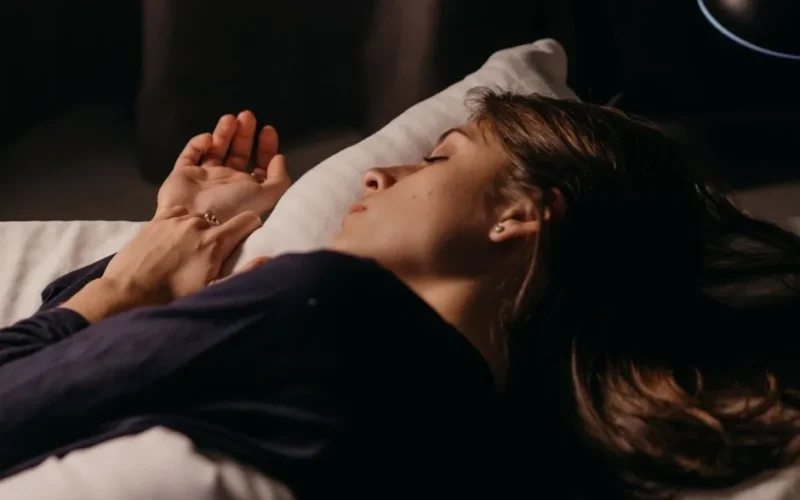A woman sleeping comfortably on a pillow in a softly lit bedroom, capturing a peaceful nighttime ambiance.
