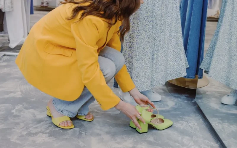 Stylish woman trying on vibrant shoes in a modern department store.