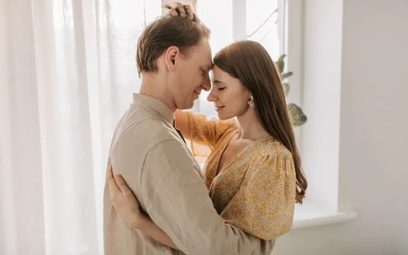 A loving couple embraces in a bright, sunlit room, exuding warmth and togetherness.