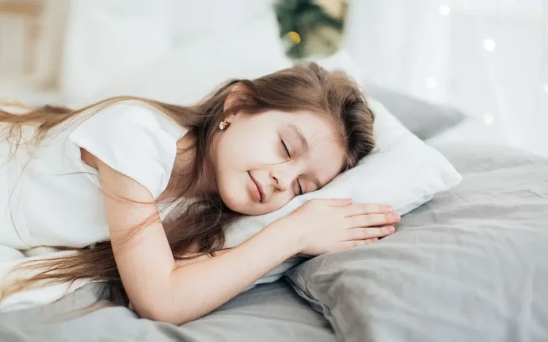 A serene portrait of a young girl peacefully sleeping on a soft pillow indoors.