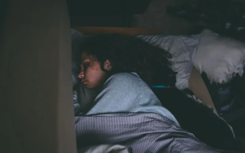 A woman sleeping peacefully with her cat, capturing a serene and cozy nighttime scene.