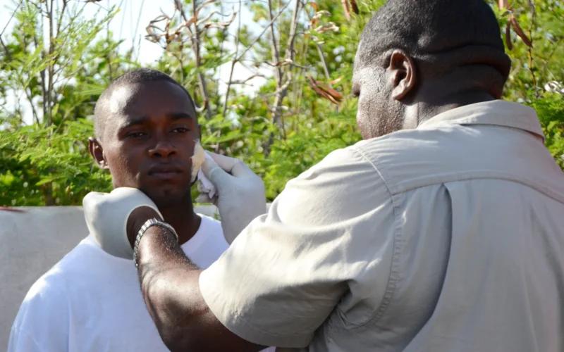 Lintin Paul, a training safety officer with Clayvue Hospital, applies moulage makeup to Ori Alleyne, a lifeguard with the Antigua and Barbuda Ministry of Tourism, before participating in a mass casualty training exercise here on June 4. Alleyne and several other lifeguards volunteered role players, depicting severely injured plane crash survivors during an Antigua and Barbuda Defence Force (ABDF) Coast Guard training exercise. The exercise tested the response capabilities of ABDF Coast Guard members in search and rescue, medical triage and treatment tactics and procedures as part of Tradewinds 2014. Tradewinds is a joint, combined exercise conducted in conjunction with partner nations to enhance the collective abilities of defense forces and constabularies to counter transnational organized crime and to conduct humanitarian/disaster relief operations. (Photo by U.S. Army Sgt. Chelsea Barber, 122nd PAOC, WAARNG)