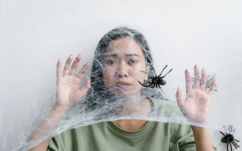 A woman caught in a web of fear, illustrating anxiety and entrapment with a spider.
