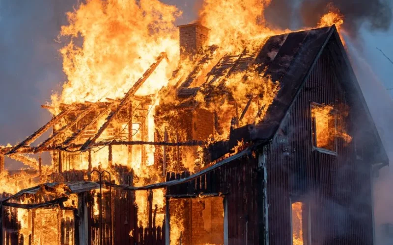 A house consumed by intense flames and smoke, capturing the power of fire.