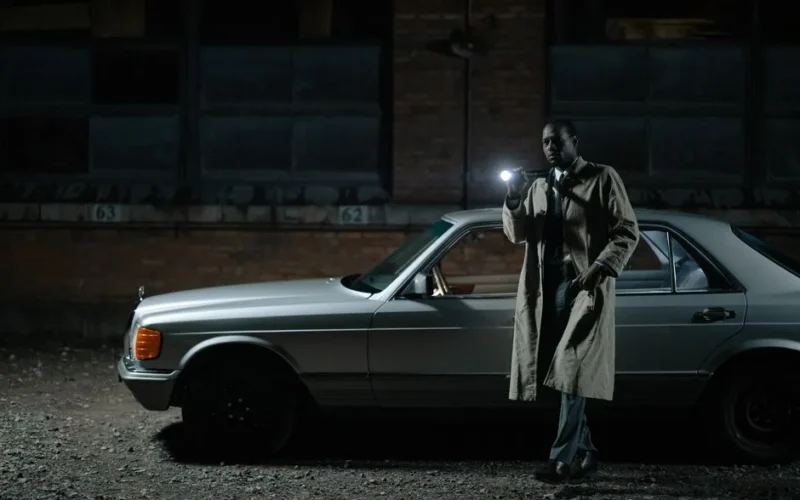 Detective conducting a night investigation by a car with a flashlight.