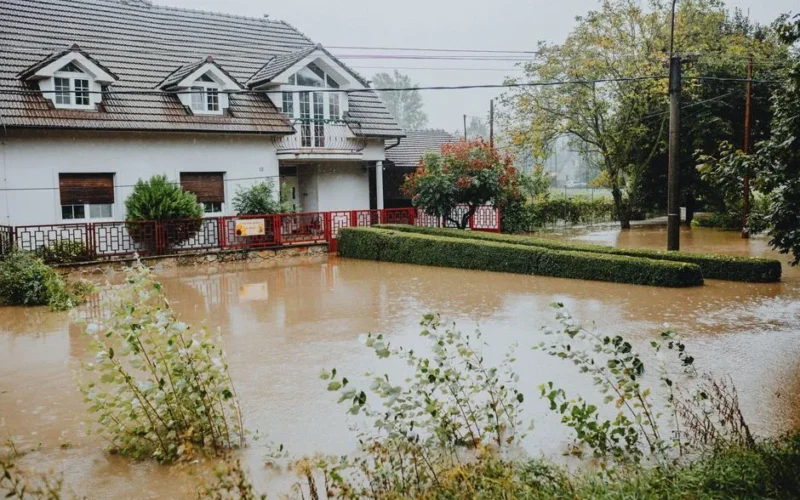 A suburban house surrounded by floodwaters after heavy rain, showing impact of natural disaster.