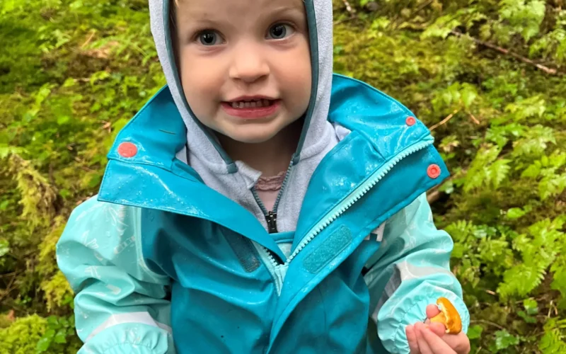 A young golden chanterelle harvester proudly showing off her picks. Tongass National Forest. Petersburg Ranger District. USDA Forest Service photo by Gina Uppencamp.