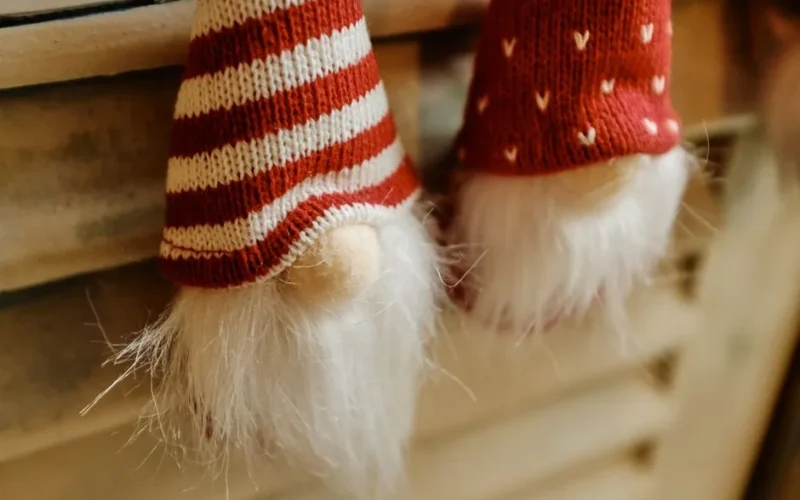 Close-up of knitted Christmas gnome ornaments in warm tones, capturing holiday spirit.