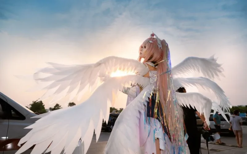 Person in angel costume with wings at a sunny outdoor event.