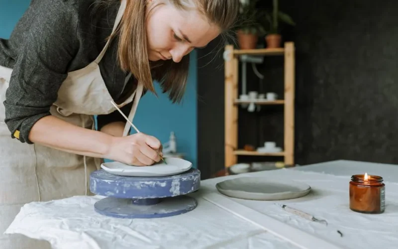 Focused woman creating pottery on a table, embodying creativity and craftsmanship.