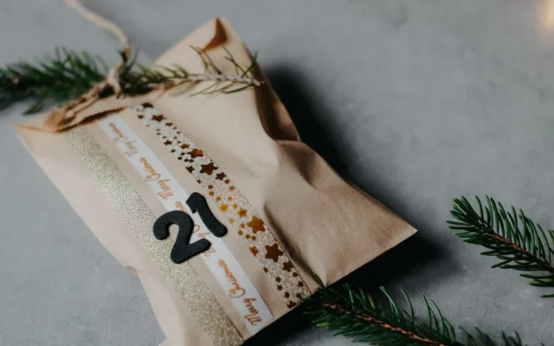 Close-up of a decorated paper bag as festive advent calendar gift on gray background.