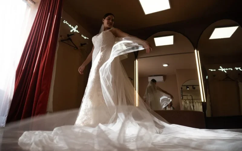 Bride in a wedding dress admiring her reflection in a chic dressing room, exuding elegance and anticipation.